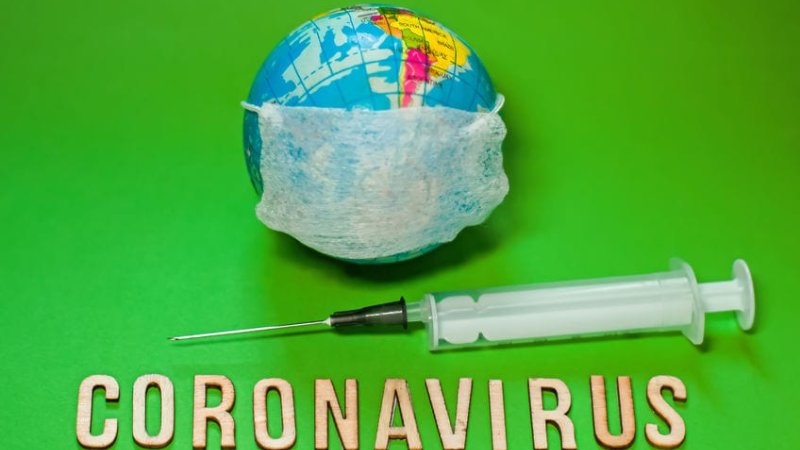 Earth planet in protective medical mask fight with text Corona virus and syringe on green background. world Corona virus attack concept. 2019 nCoV virus infection originating in Wuhan, China