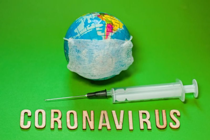 Earth planet in protective medical mask fight with text Corona virus and syringe on green background. world Corona virus attack concept. 2019 nCoV virus infection originating in Wuhan, China